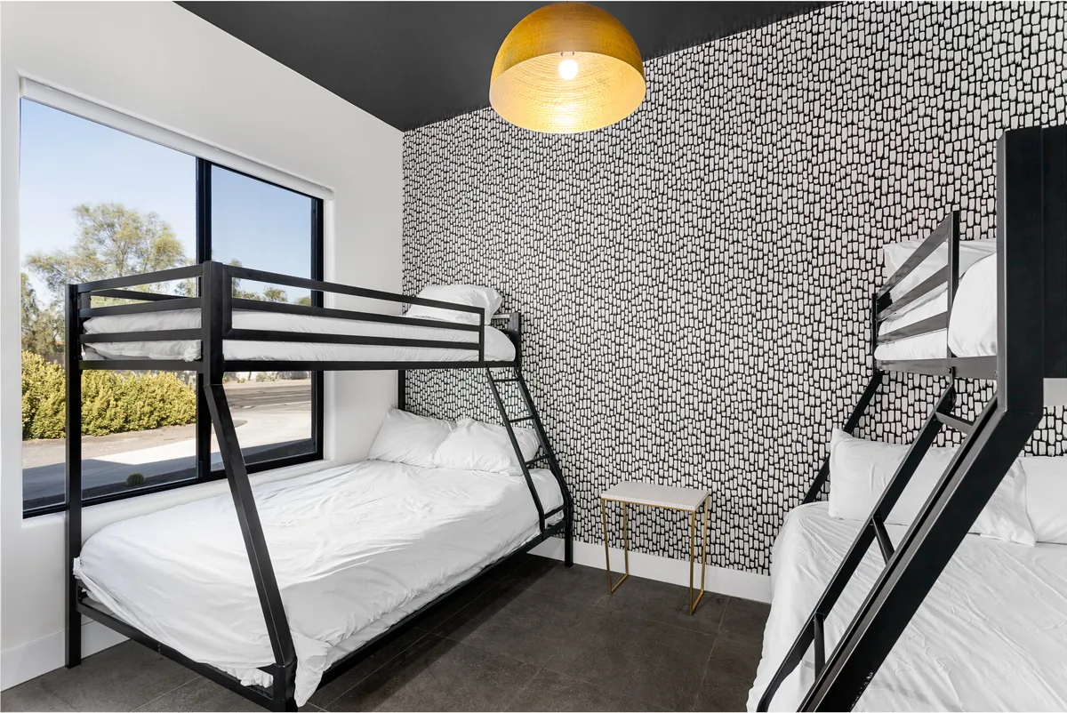 A cheerful kid-friendly bedroom outfitted with sturdy bunk beds, a textured accent wall, and playful lighting. The space is casual and designed for both fun and restful sleep, ideal for younger guests or families.
