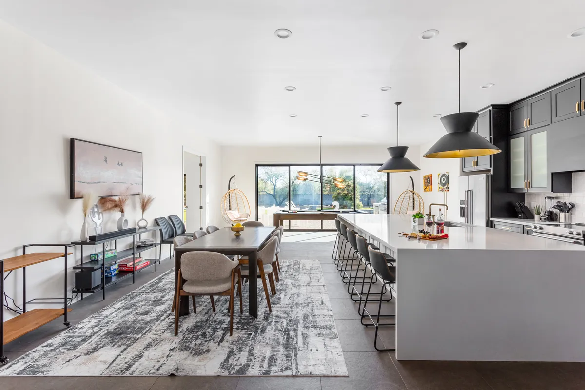 The spacious kitchen and dining area includes a large kitchen island, a dining table, and floor-to-ceiling windows that flood the space with light. Stylish pendant lighting and modern finishes create an inviting, functional hub ideal for families and groups to gather, dine, and socialize.